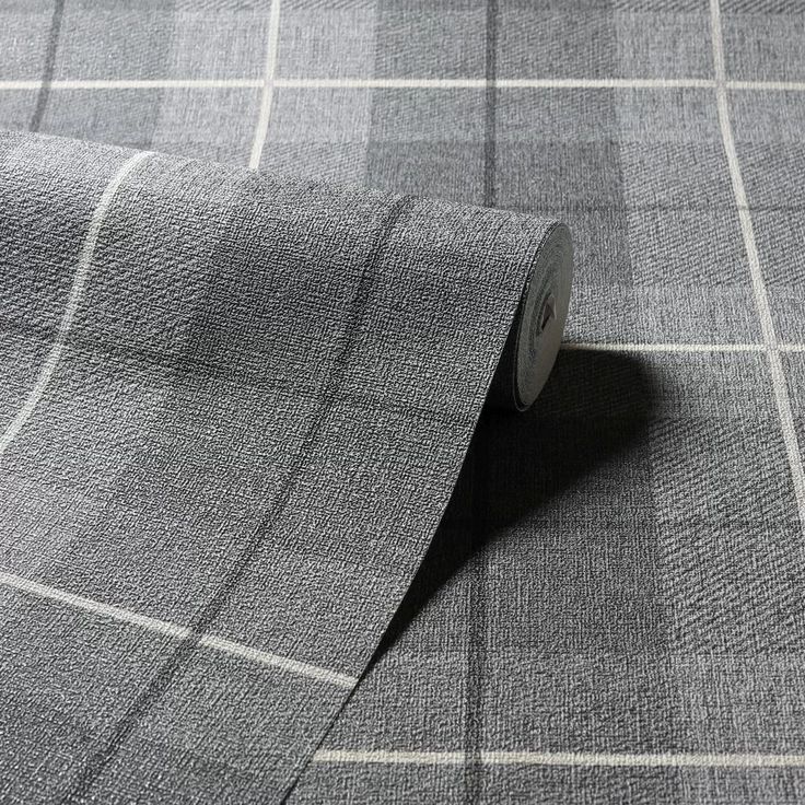 a roll of gray fabric on top of a table with a white and black checkered pattern