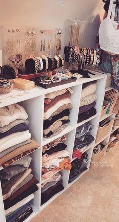 a woman standing in front of a closet filled with clothes and other items on shelves