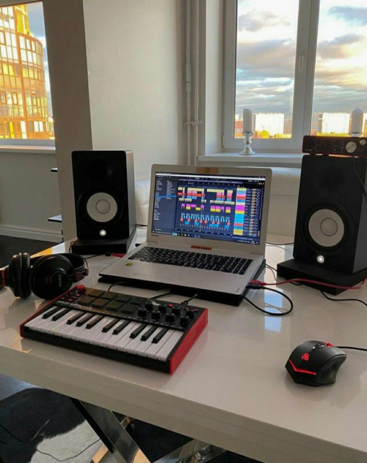 a laptop computer sitting on top of a desk next to a keyboard and headphones