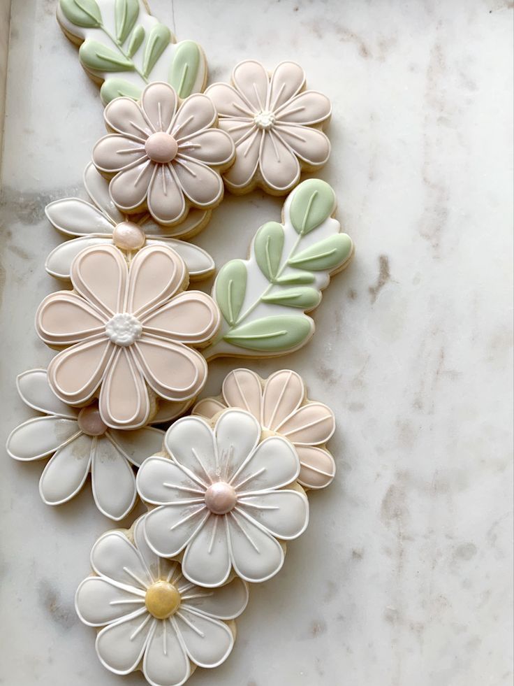 cookies decorated with flowers and leaves on a marble surface