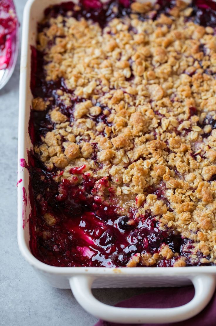 blueberry cobbler with crumbs in a white baking dish on a table