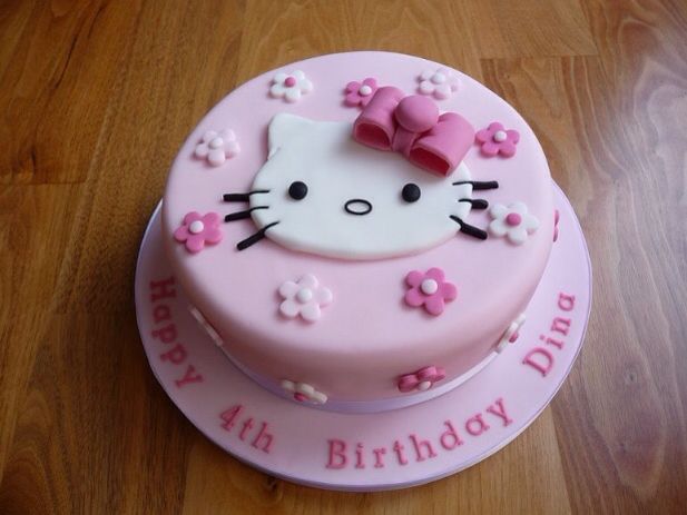 a pink hello kitty birthday cake on a wooden table