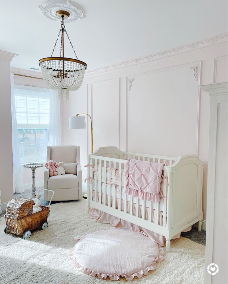 a baby's room with a crib, rocking chair and chandelier