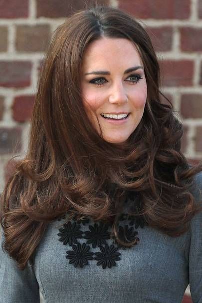 a woman with long brown hair wearing a gray dress