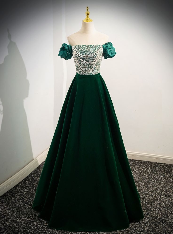 Adorning grace and beauty, could this gown be the embodiment of a forest fairy tale come to life? The dress sweeps the floor with its rich emerald green velvet, reminiscent of the deep, enchanting woods. The bodice is a work of art, meticulously beaded with delicate patterns that resemble intricate vines and leaves, celebrating nature's own elegance. Puffed sleeves in a matching shade of green add a touch of whimsical charm, perfect for an evening where every detail tells a story. This gown is d Gold Prom Dresses Long, Green Long Prom Dress, Velvet Prom Dress, Gold Prom Dresses, Long Formal Dress, White Prom Dress, Formal Evening Dress, Evening Dress Fashion, Short Prom Dress