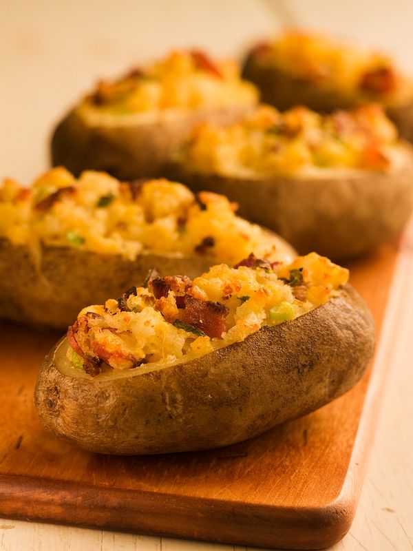 three baked potatoes sitting on top of a wooden cutting board