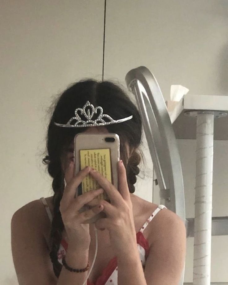 a woman is taking a selfie with her cell phone wearing a tiara and dress