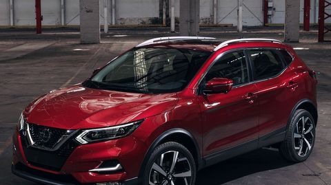 a red nissan suv parked in an empty parking lot