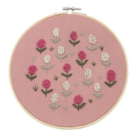 a pink embroidery kit with white and pink flowers on the front, in an embroidered hoop