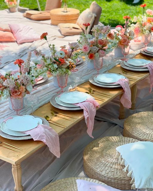 a table set up with plates and vases filled with flowers on top of it