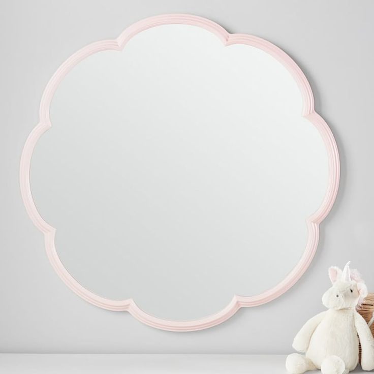 a stuffed animal sitting next to a large mirror on a wall with a pink frame