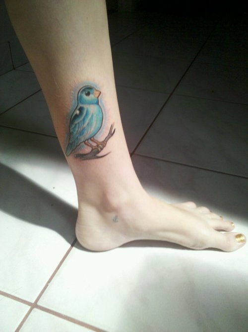 a small blue bird tattoo on the ankle