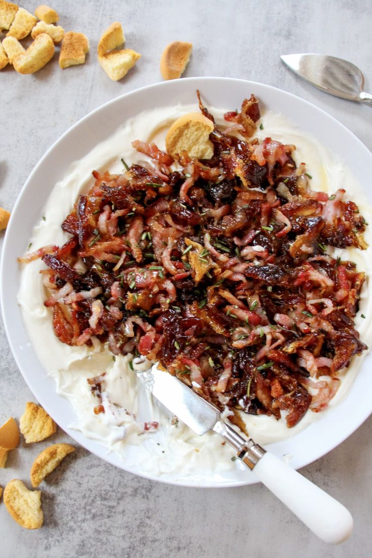 a white plate topped with mashed potatoes covered in toppings next to crackers