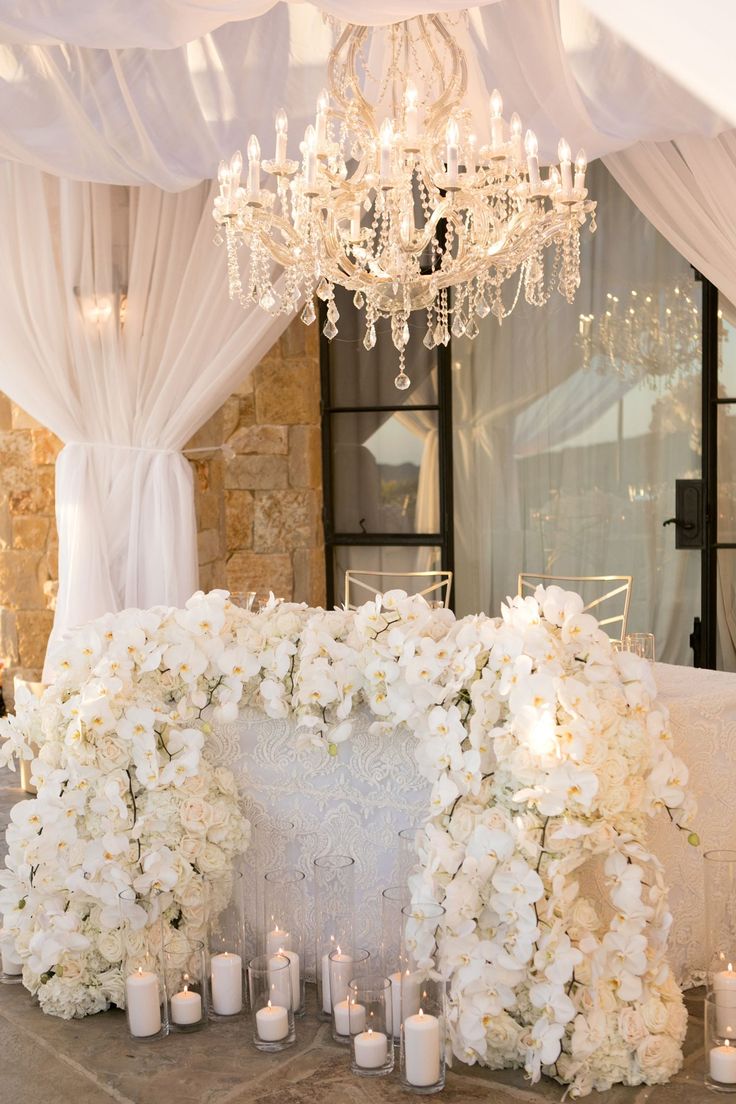 a wedding ceremony with white flowers and candles on the floor in front of a chandelier