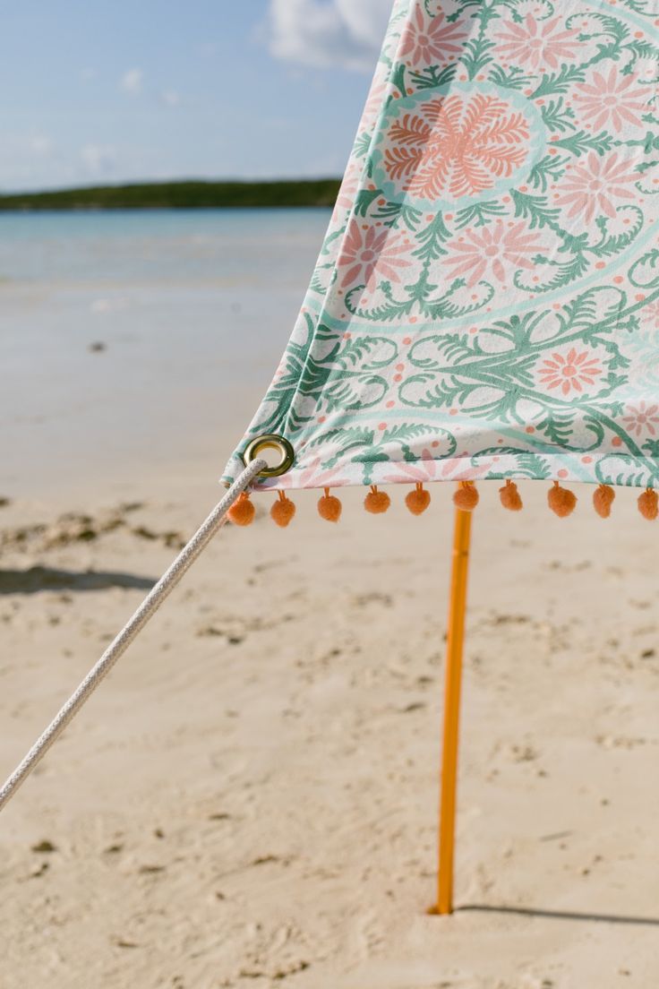 an umbrella is on the beach near the water and sand with pom - poms