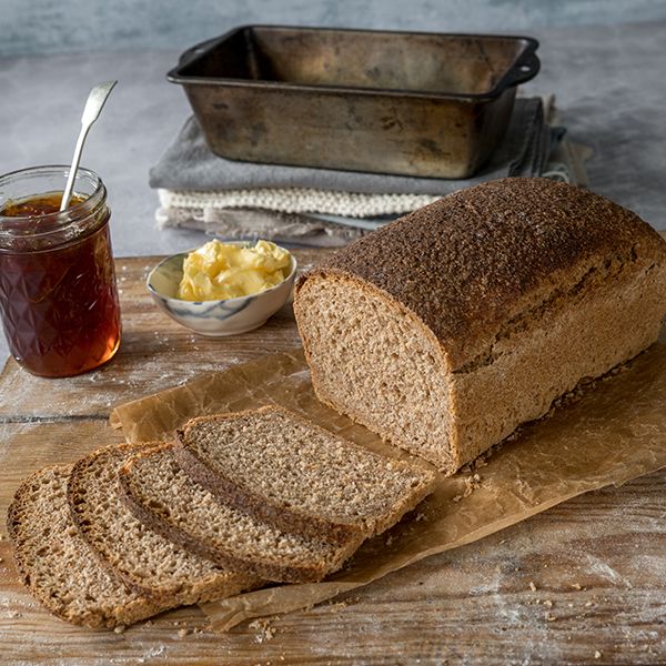 a loaf of bread sitting on top of a cutting board next to a bowl of butter