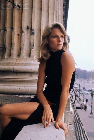 a woman sitting on top of a stone wall next to pillars and columns in the background