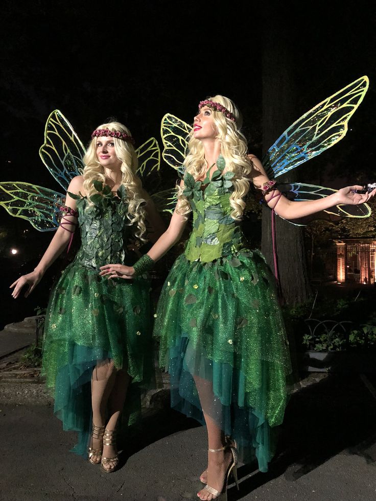 two women dressed as tinkerbells standing next to each other in the dark