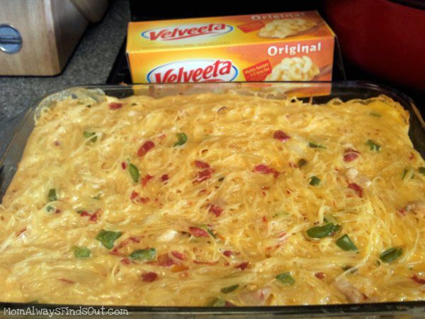 a casserole dish with cheese and vegetables in it next to a box of velveeta