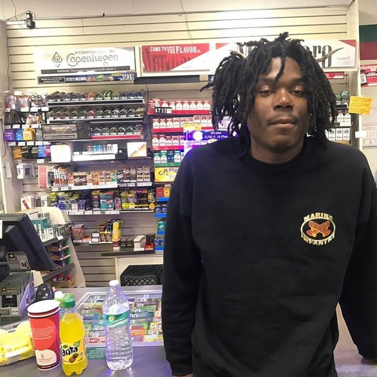 a man with dreadlocks standing in front of a counter at a pharmacy store