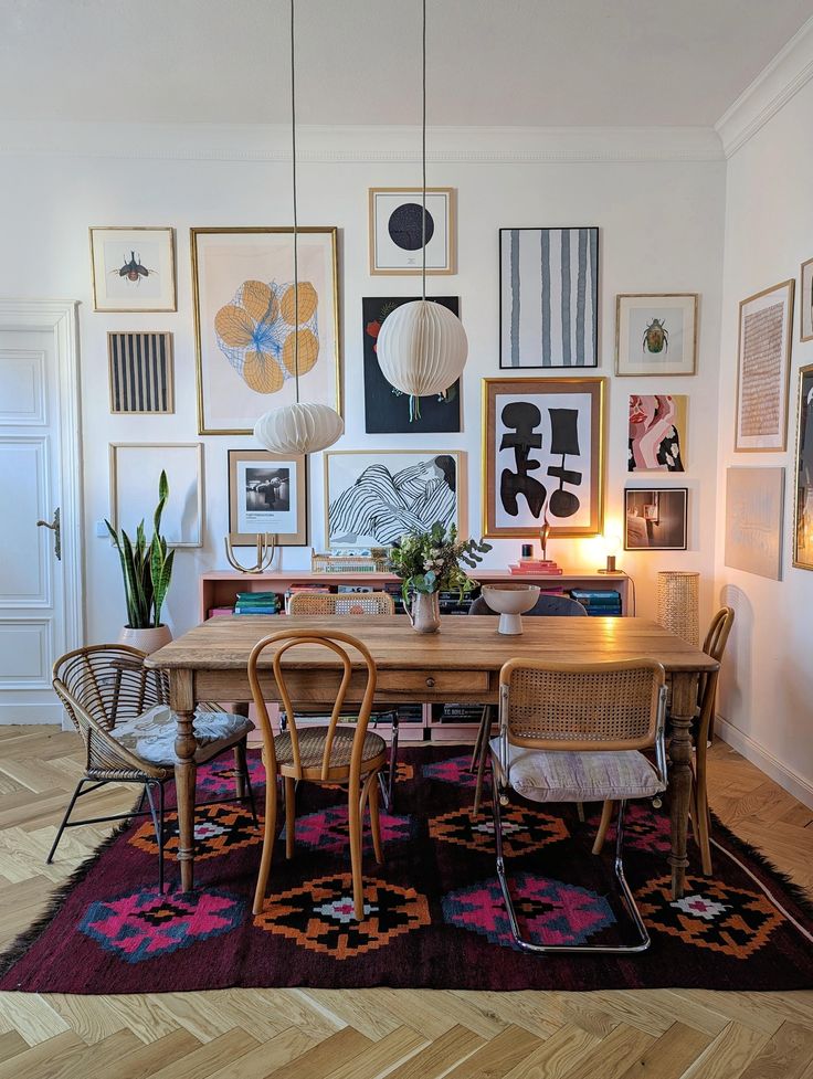 a dining room table with chairs and pictures on the wall in front of it,