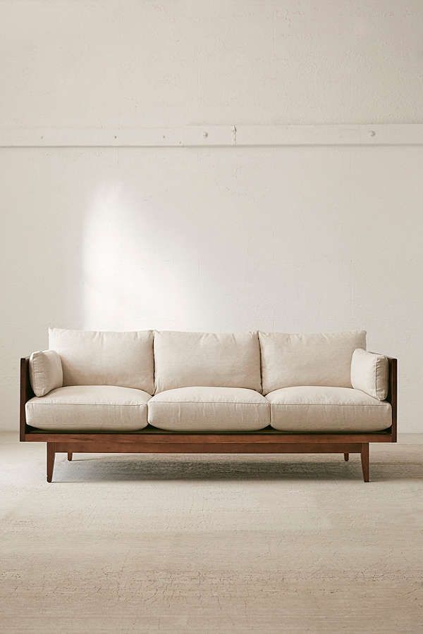 a white couch sitting on top of a hard wood floor next to a window in an empty room