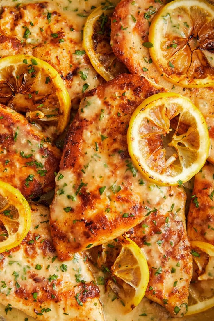 a pan filled with chicken covered in cheese and lemon slices