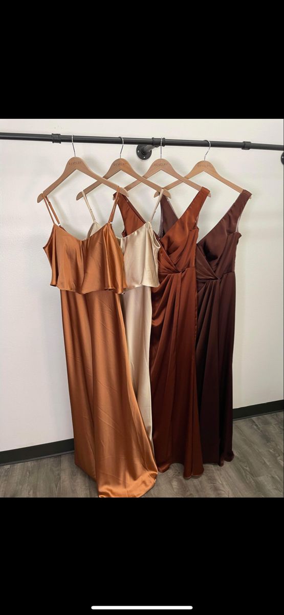 three dresses hanging up against a wall