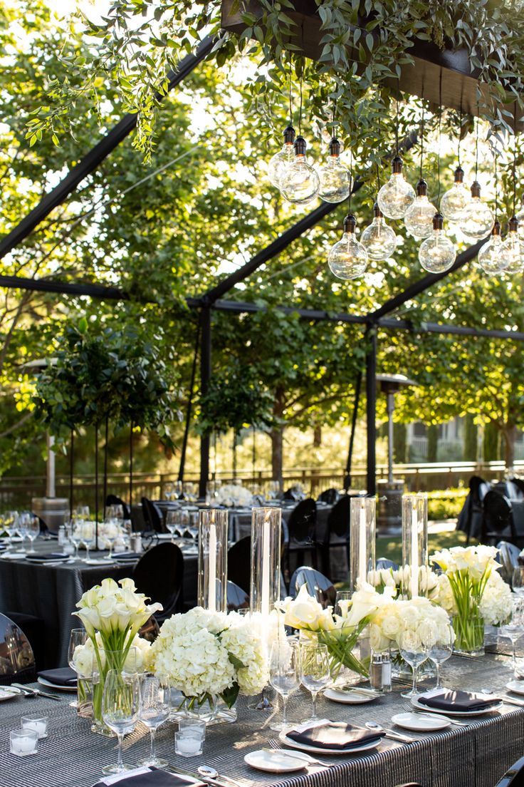 an outdoor dining area with tables, chairs and centerpieces