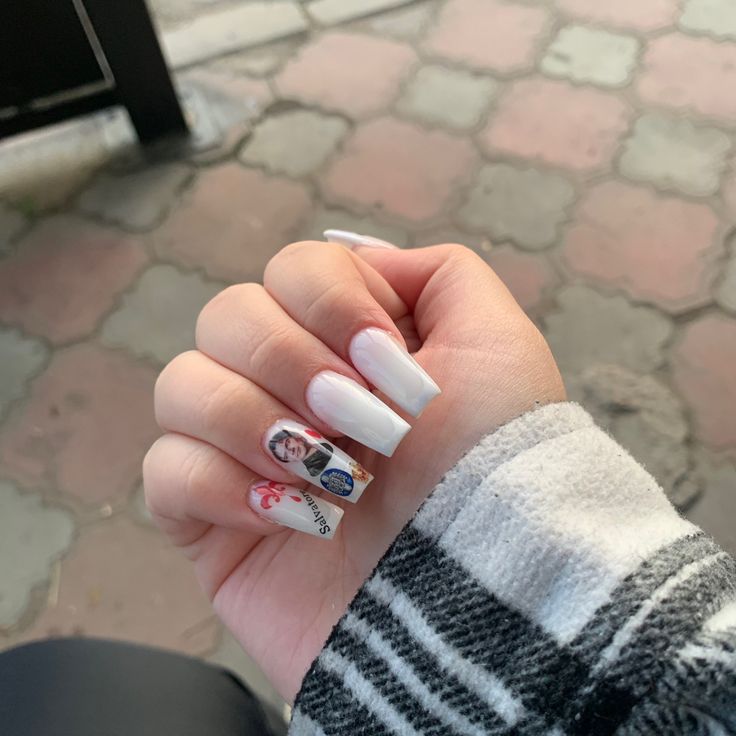 a woman's hand with white and black nail polish on it