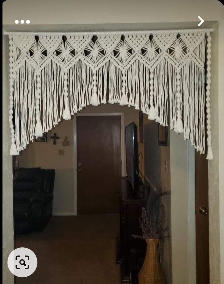 a white curtain with tassels hanging from it's side in a living room