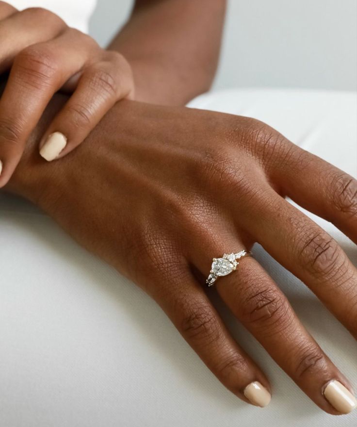 a close up of a person's hand with a diamond ring on their finger