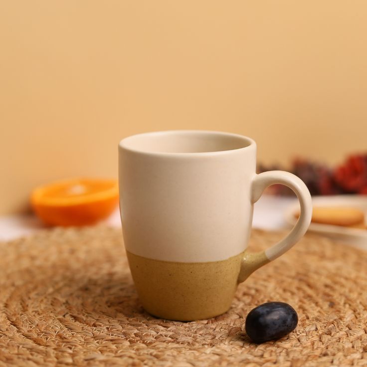 a coffee cup sitting on top of a placemat next to some berries and oranges