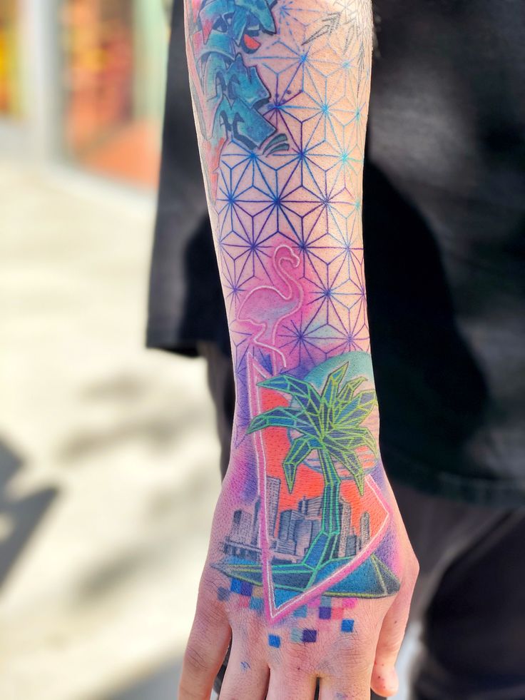 a person with a colorful tattoo on their arm holding onto his hand and palm trees in the background