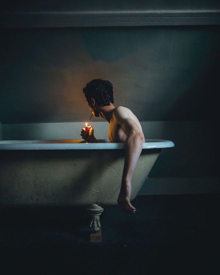 a man sitting in a bathtub holding a candle