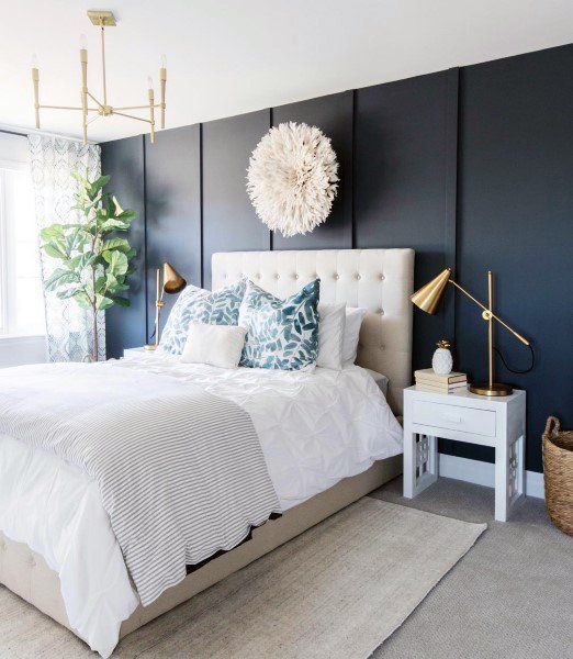 a bed with white sheets and pillows in a room that has dark blue painted walls