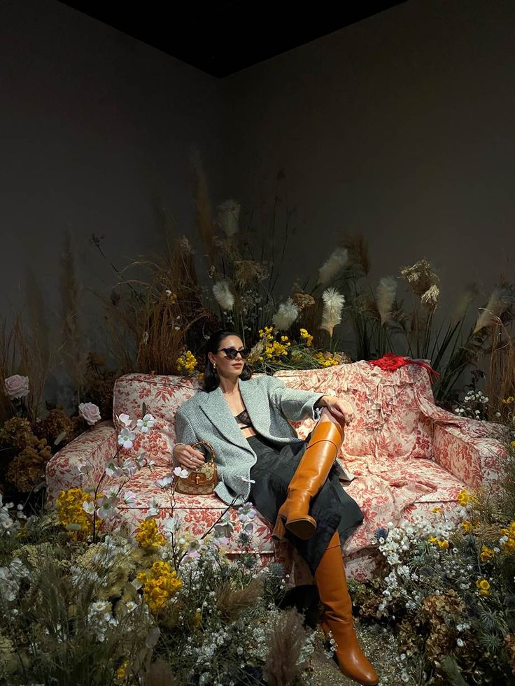 a woman sitting on top of a couch surrounded by flowers