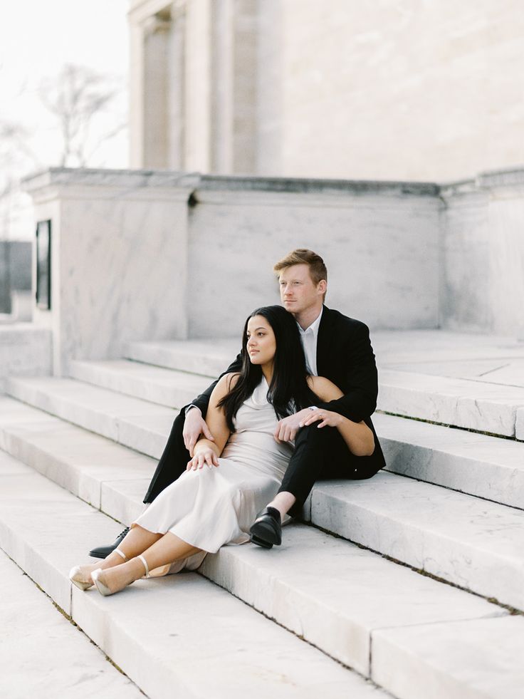 a man and woman sitting on steps in front of a building