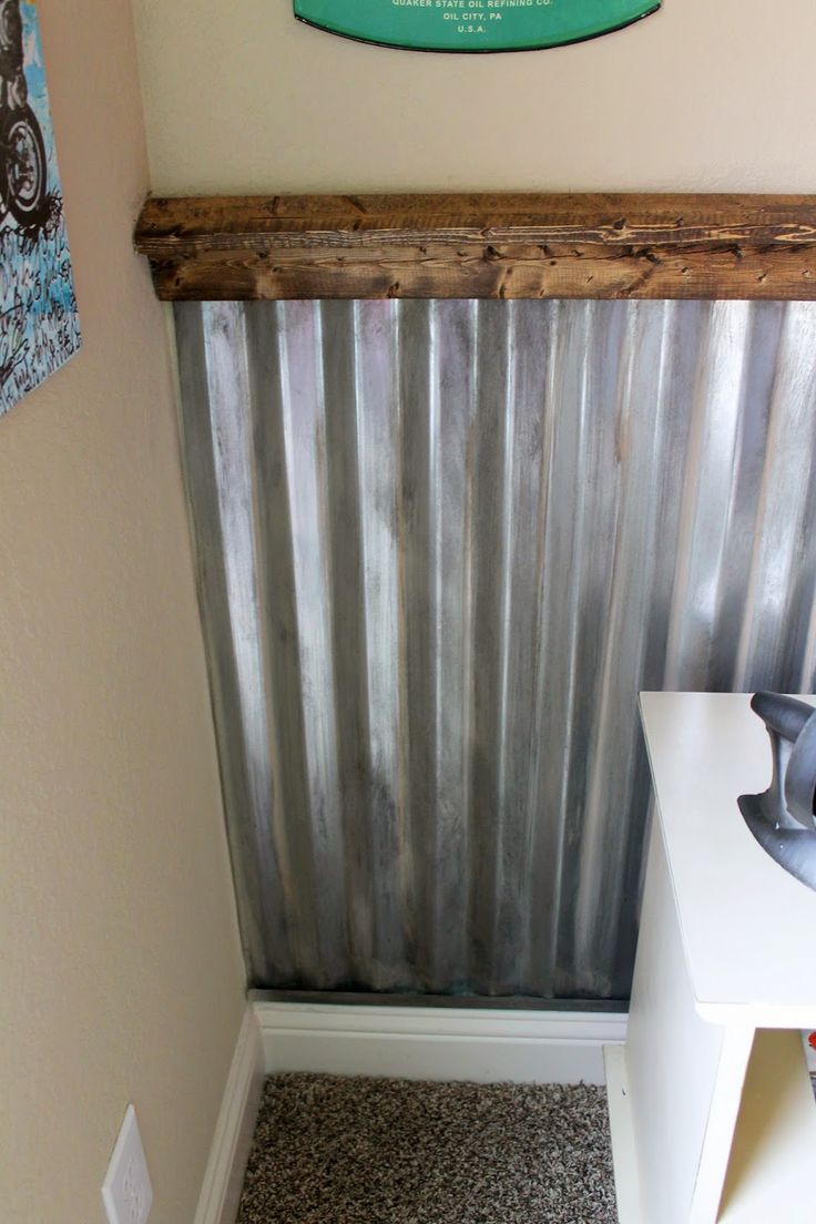 a bathroom with a sink and mirror next to a metal paneled wall behind the toilet