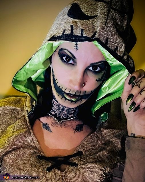 a woman with makeup on her face is wearing a green hoodie and black nails