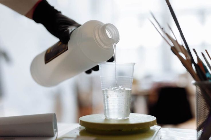 a person pouring water into a glass on top of a table