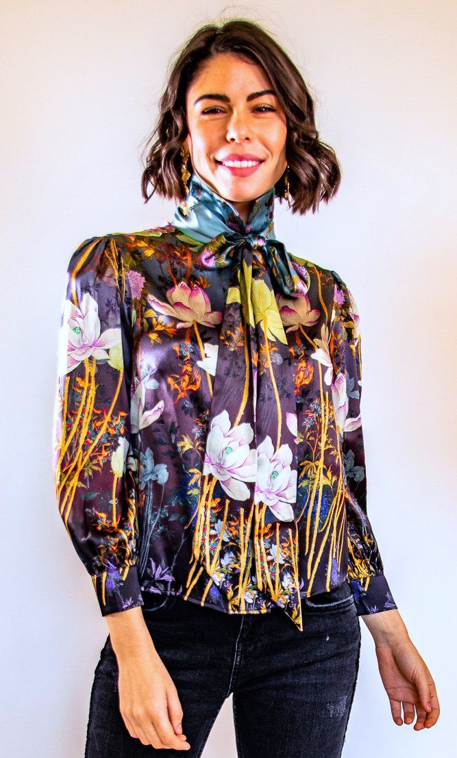 Romance is in full bloom in Trisha's spring/summer 2019 Collection. This beautiful pure silk blouse is decorated with delicate flowers that cascade down the body. Fun design elements are emphasized by a front tie and high collar. There is nothing like a touch of romance intertwined with the fresh bloom of spring. This blouse can be worn all season and very elegantly or casually. Don't be a stranger! Call us, text us, email us and we will gladly help you find the perfect dress! Email: Trisha@tris Luxury Blouse, Romantic Essence, Cascading Flowers, Work Outfits Women Summer, London Fashion Week Street Style, Summer Work Outfits, London Street Style, Delicate Flowers, Bow Blouse