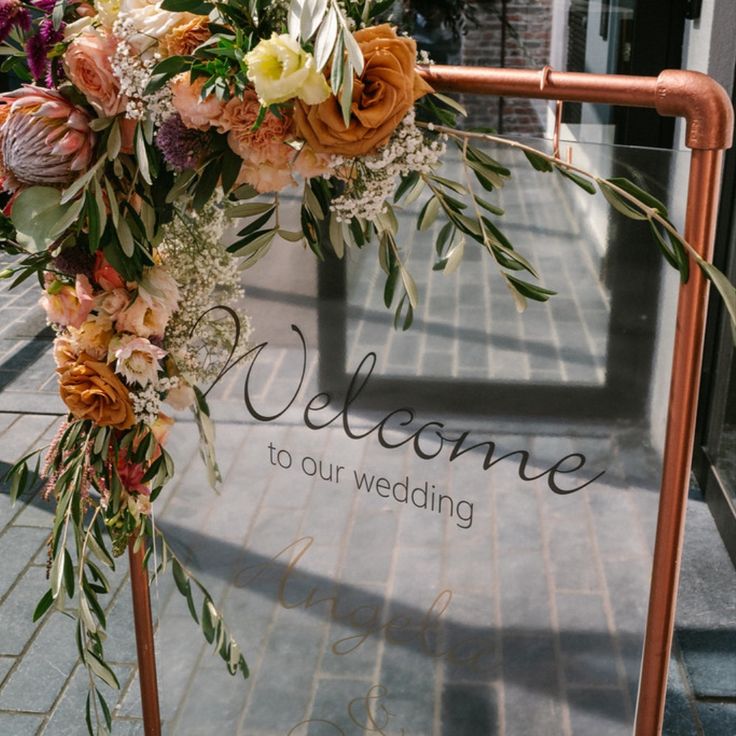 a welcome sign is decorated with flowers and greenery