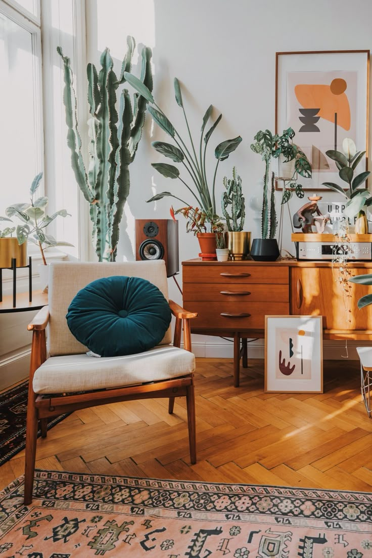 a living room filled with lots of plants next to a wooden dresser and chair on top of a hard wood floor