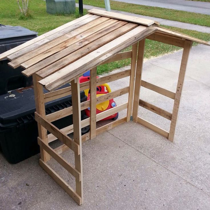 a child's play house made out of pallets and wooden slats on the sidewalk