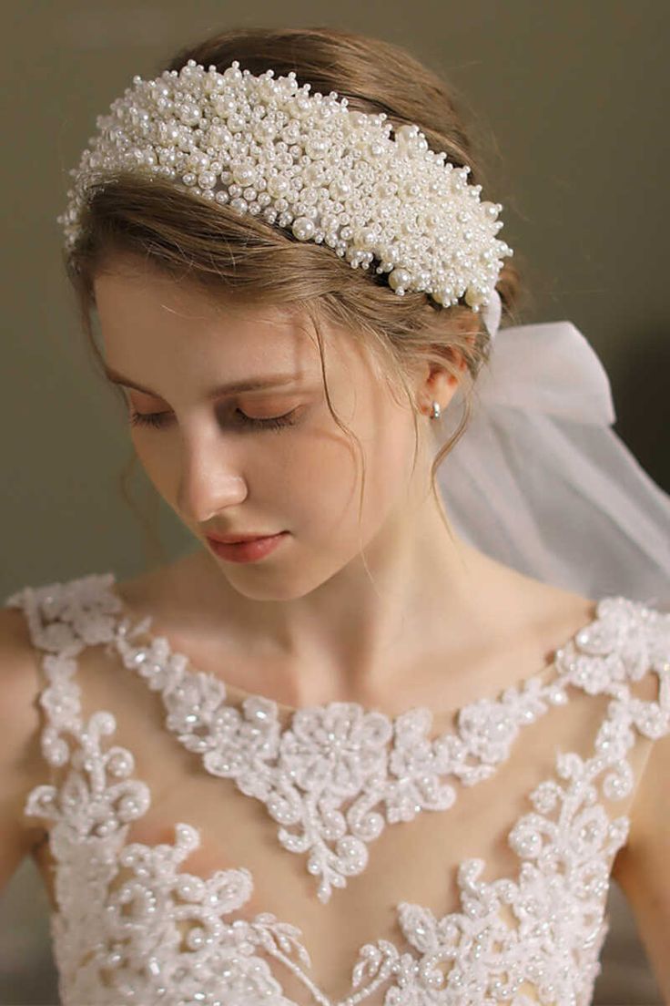 a woman in a wedding dress wearing a head piece with pearls on it's side