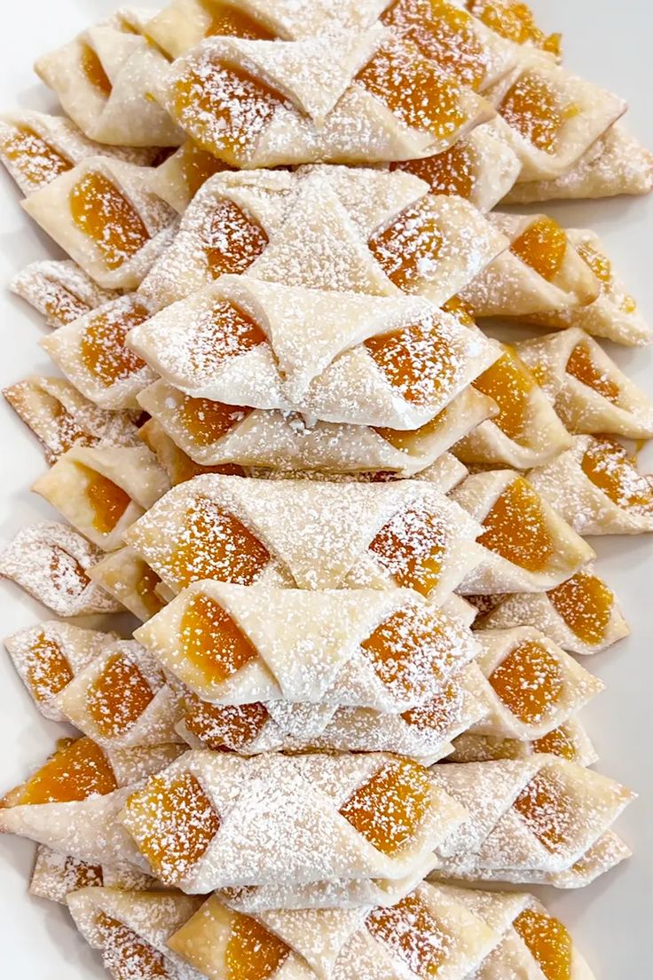 several small pastries are arranged on a white platter with powdered sugar toppings