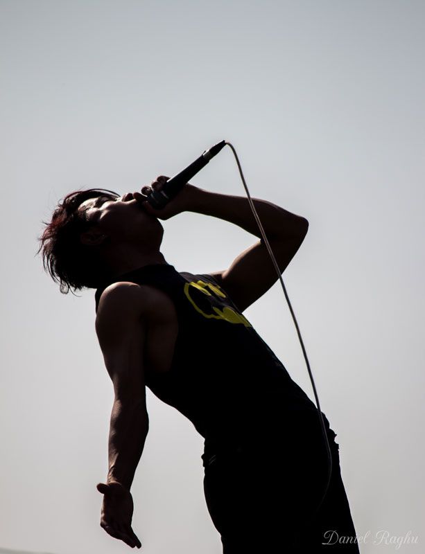 a man holding a microphone up to his face while standing on top of a hill