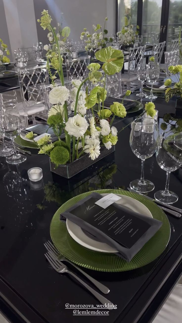 the table is set with green and white plates, silverware, and vases