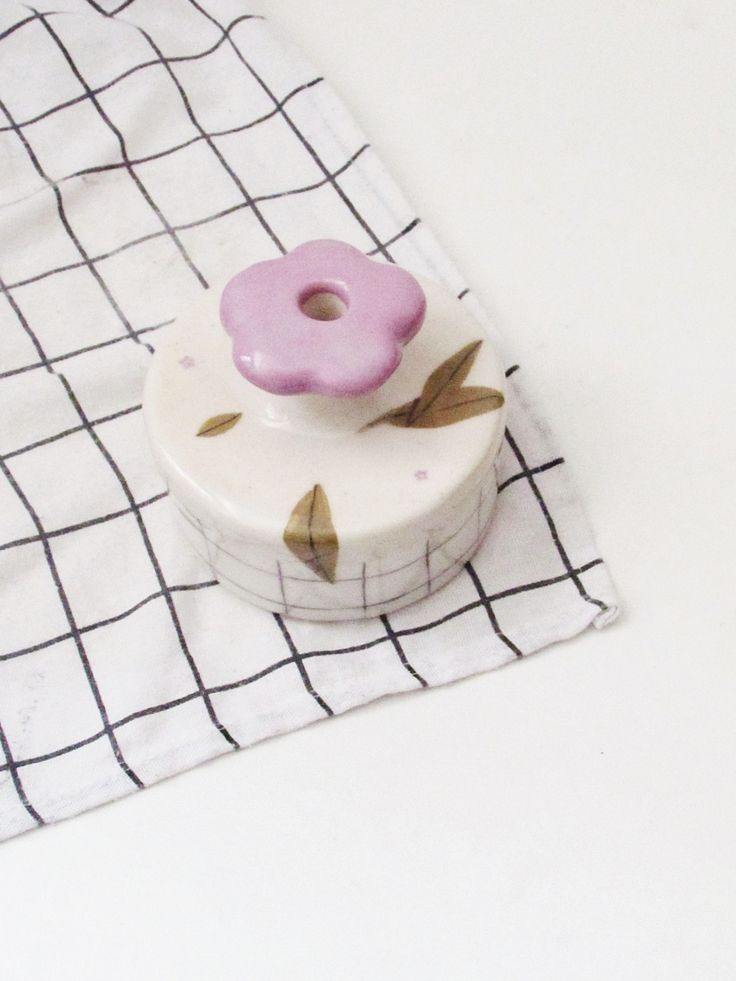 a white and pink object sitting on top of a checkered table cloth next to a cup